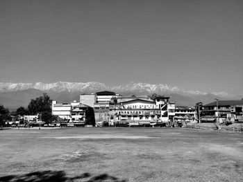 Houses on field by buildings against sky