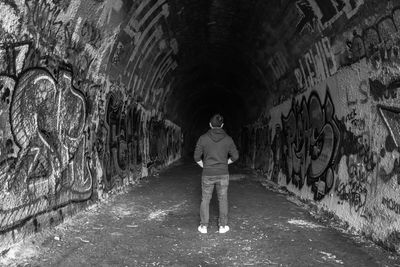 Rear view of man standing in tunnel amidst buildings