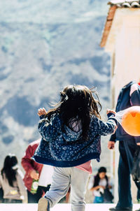 Rear view of girl running on road during sunny day