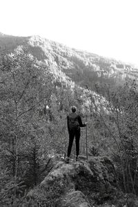 Rear view of man standing on mountain against sky