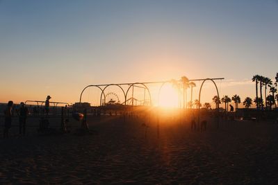 Silhouette people at beach against sky during sunset