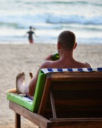 Man sitting on lounge chair at beach