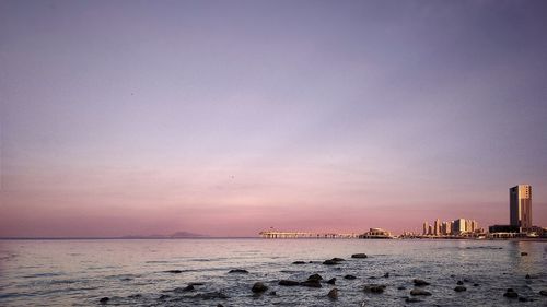 Scenic view of sea and buildings against sky during sunset