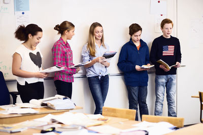 High school students studying against whiteboard in classroom