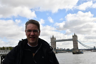 Portrait of man standing by suspension bridge