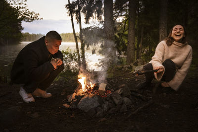 Friends sitting by campfire in forest