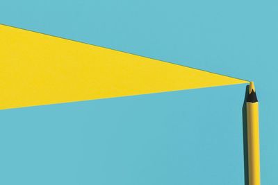 Low angle view of yellow paper against blue sky