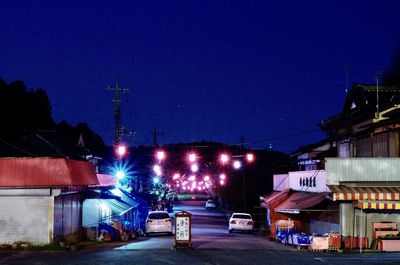 Illuminated road against blue sky at night