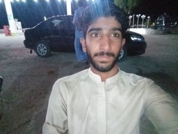 Portrait of young man standing by car