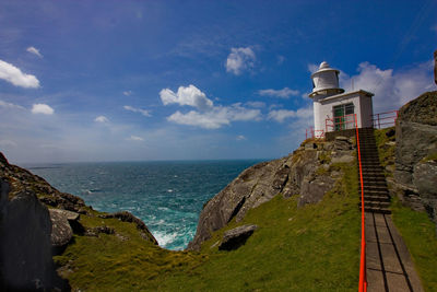 Lighthouse by sea against sky