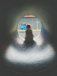 Rear view of boy sitting in tunnel slide