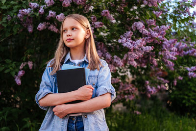 Portrait of young woman standing against plants