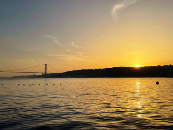 Bridge over sea against sky during sunset