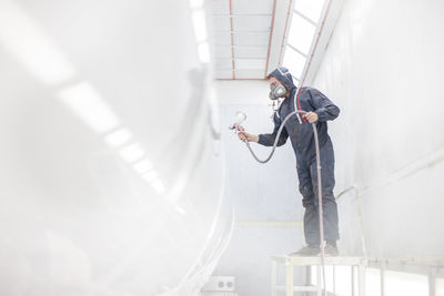 Industrial worker spray painting and wearing protective clothing