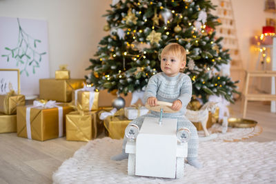 Portrait of cute girl standing by christmas tree