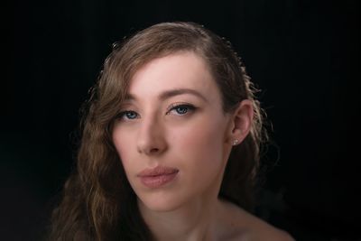 Portrait of young woman against black background