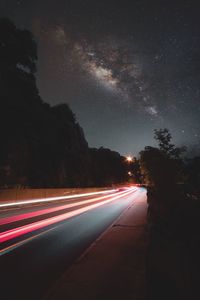 Light trails on road against sky at night