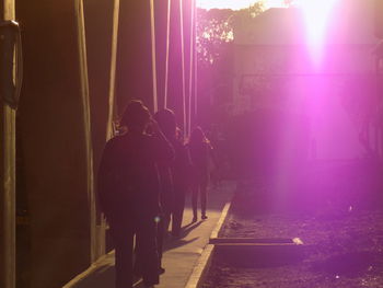 Rear view of people walking on illuminated footpath at night