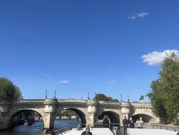Arch bridge over river against blue sky