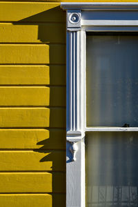 Detail of carved wood window frame painted white on exterior yellow victorian house