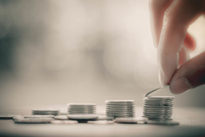 Close-up of hand holding coin stack on table