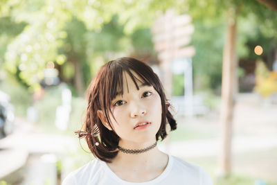 Close-up portrait of young woman with bangs in park