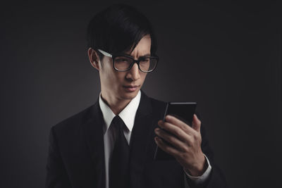 Young man using smart phone against black background