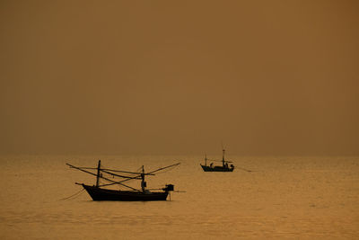 Sailboat sailing in sea against sky during sunset