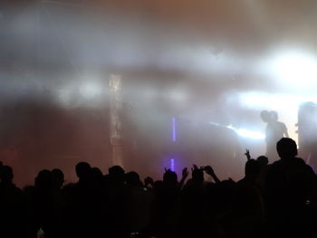 Silhouette people at music concert against sky at night