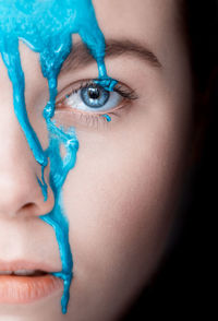 Close-up portrait of woman with blue paint on face