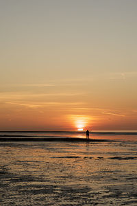 Silhouette people on beach against sky during sunset