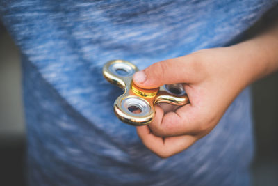 Midsection of boy holding golden fidget spinner