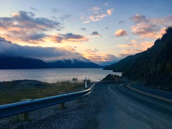 Road by sea against sky during sunset