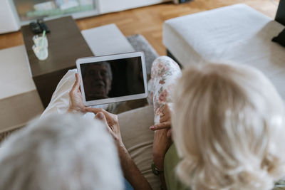 Senior couple at home sitting on couch sharing tablet