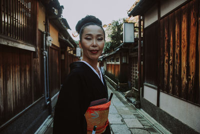 Smiling young woman standing against building