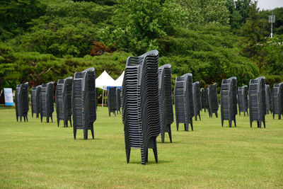 Empty chairs stacked over grass field