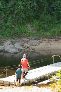 Rear view of father with children walking on footbridge