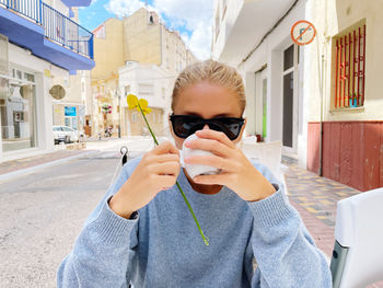 Young woman sitting at the cafe holding coffee cup