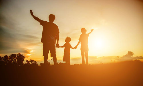 Silhouette people standing against sky during sunset