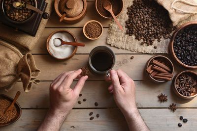 High angle view of hand holding coffee cup on table