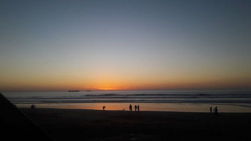 Scenic view of beach against clear sky during sunset