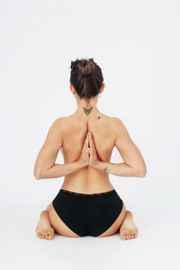 Rear view of woman sitting against white background