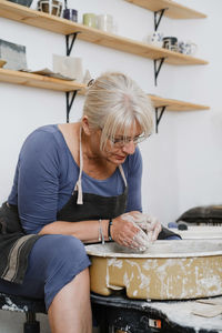 Woman rolling clay, making ceramic plate in studio with floral pattern. handmade creative work