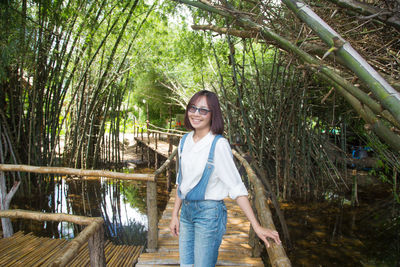 Portrait of smiling young woman standing on boardwalk at park