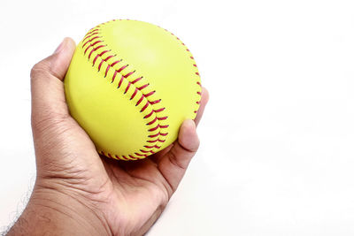 Close-up of cropped hand holding yellow object over white background