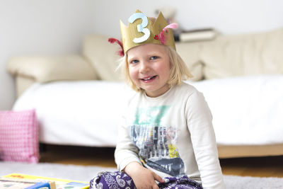 Portrait of happy girl sitting on floor at home