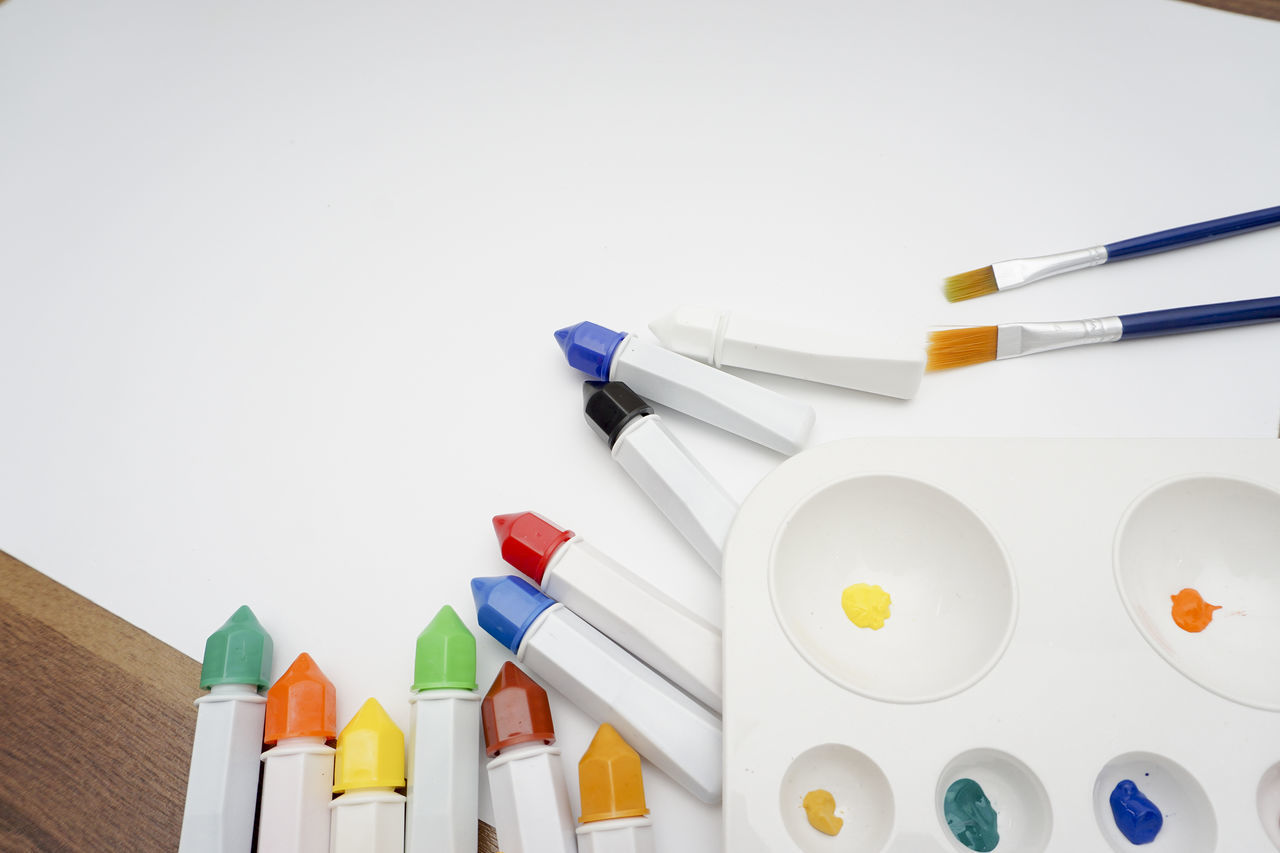 HIGH ANGLE VIEW OF COLORED PENCILS ON WHITE TABLE