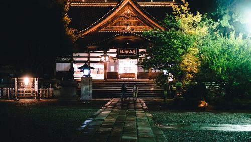 Illuminated building by lake at night