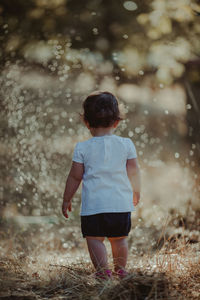 Rear view of baby girl standing on land