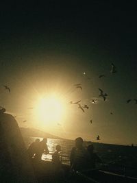 Silhouette people on beach against clear sky during sunset